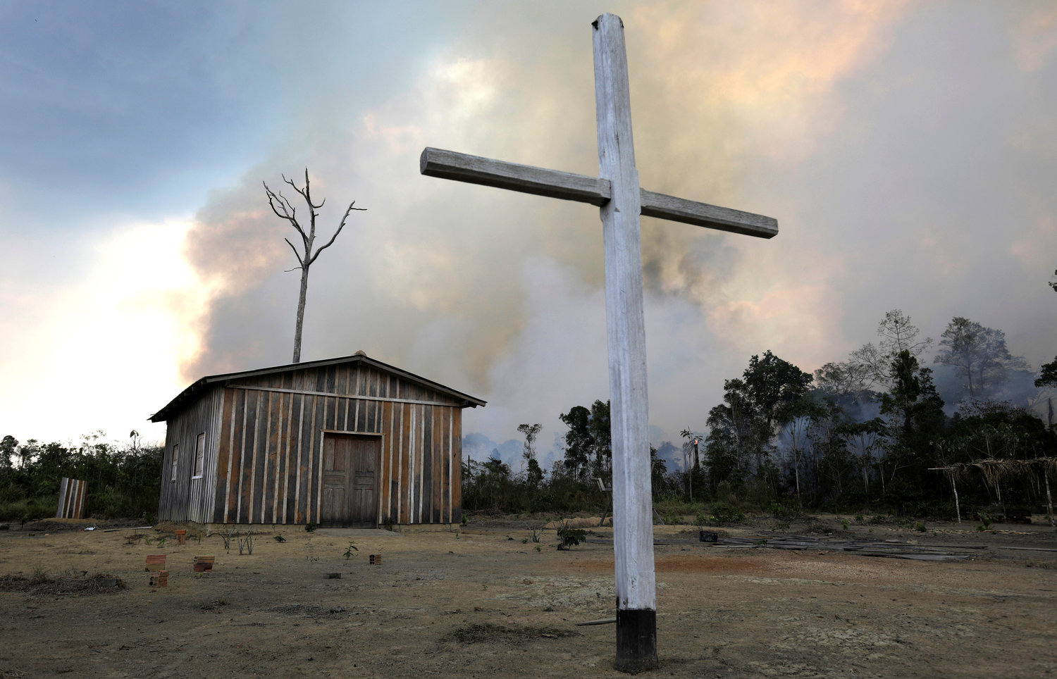 A wooden cross is seen in front of a Catholic church as a fire burns a tract of the Amazon jungle being cleared by loggers and farmers near Porto Velho, Brazil, Aug.27, 2019. The Vatican released Pope Francis’ post-synodal apostolic exhortation, “Querida Amazonia” (Beloved Amazonia), Feb. 12, 2020.